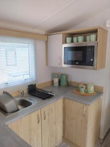 a small kitchen with a sink and a microwave at Luxury 6 berth Caravan Lytham in Preston +9 photos