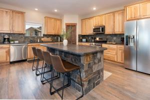 a kitchen with a large stone island with bar stools at Pool Table, Expansive Mountain Views, New Construction, Close to Town in Grand Lake
