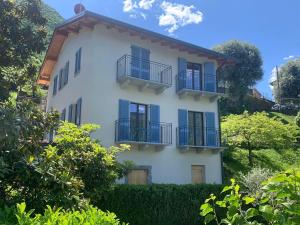 a white house with blue windows and balconies at Il Porticciolo in Lezzeno