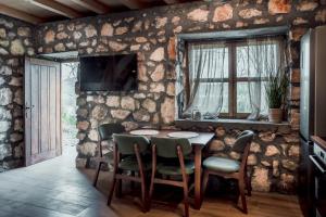 a dining room with a table and chairs and a television at Arhetip, Djedova Villa in Žabljak