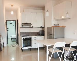 a kitchen with white cabinets and a table and chairs at Lara´s house in Agios Nikolaos