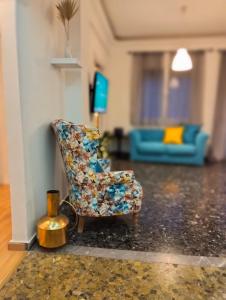 Una sala de estar con una silla y un sofá azul. en ilios - urban suite, city center, en Heraclión