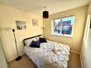 a bedroom with a bed with blue pillows and a window at Torwood Townhouse - SuperFast WiFi, Contractor Friendly with Free Parking in Edinburgh