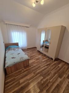 a bedroom with a bed and a wooden floor at Gulu Cottage House in Mərdəkan