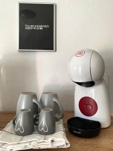 a coffee maker and three cups on a table at 4 Roses Residence VRTNICA in Sečovlje