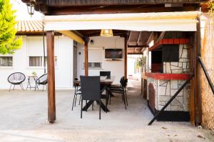 eine Terrasse mit einem Tisch, Stühlen und einem Kamin in der Unterkunft MareAntoanetta in Nea Kallikratia