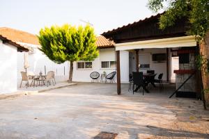 eine Terrasse mit Stühlen und einem Tisch und einem Baum in der Unterkunft MareAntoanetta in Nea Kallikratia