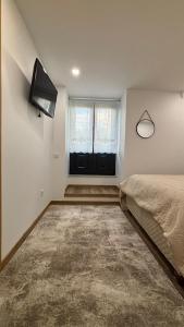 a bedroom with a bed and a tv and a window at As Casas do Penedo da Moura in Arcos de Valdevez