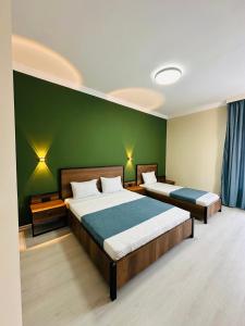 two beds in a room with green walls at Hotel albatros shekvetili in Shekhvetili +28 photos