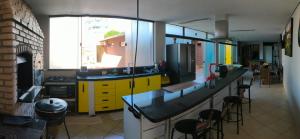 a kitchen with yellow cabinets and a counter with stools at Lindo espaço de lazer in Cascavel