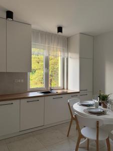a kitchen with white cabinets and a table and a window at Widok Kielce - Góry Świętokrzyskie in Kielce