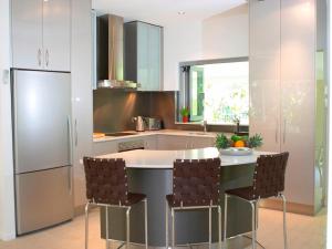 a kitchen with a island with chairs around it at Aquatica - Luxe Holiday Home in Palm Cove