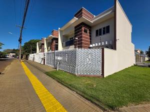 a house with a white fence and a yellow curb at Sobrado ao lado Paraguai garagem e churrasqueira in Foz do Iguaçu