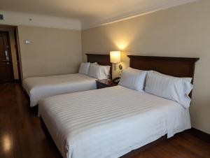 two beds in a hotel room with white sheets at Hotel Estelar La Fontana in Bogotá