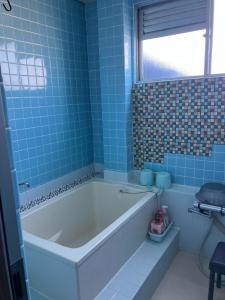 津山市にあるTogawa Nojuku - Vacation STAY 49387vの青いタイル張りのバスルーム(バスタブ付)、窓が備わります。