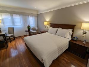 a bedroom with a large white bed and a desk at Hotel Estelar La Fontana in Bogotá