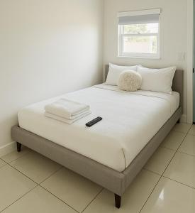 a bed with white sheets and a remote control on it at Tempurpedic Queen - Laundry, Parking & EV Charger in Hollywood