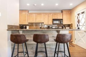 a kitchen with wooden cabinets and two bar stools at Private Hot Tub and Sauna, Right on Fairway, Minutes From Vail Village & Golden Peak in Vail
