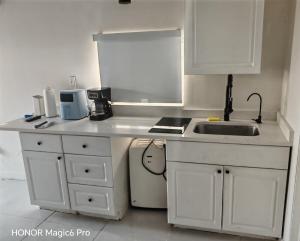 a kitchen with white cabinets and a sink and a stove at Tempurpedic Queen - Laundry, Parking & EV Charger in Hollywood