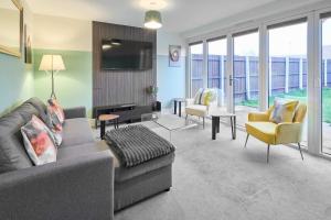 ein Wohnzimmer mit einem Sofa, Stühlen und einem TV in der Unterkunft Modern Home with Garden, Corby in Corby and Weldon