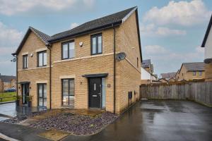ein Backsteinhaus mit schwarzer Tür auf einem Parkplatz in der Unterkunft Modern Home with Garden, Corby in Corby and Weldon