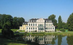a large white house with a pond in front of it at Schöne Wohnung in ruhiger Gegend in Calden