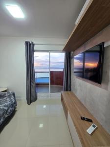 a bedroom with a large window with a view of the ocean at Apartamento em Arraial do Cabo in Arraial do Cabo