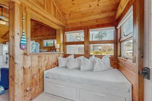 a bed in a room with wooden walls and windows at Glendon Beach Getaway in Dennis