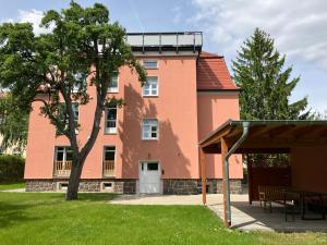 ein großes rosafarbenes Gebäude mit einem Baum davor in der Unterkunft Apartment-Haus Landeskrone in Dresden