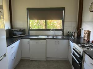 a kitchen with white cabinets and a sink and a window at Waterview Cottage in Baffle Creek