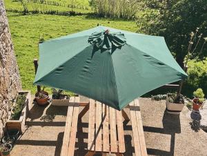 a green umbrella sitting on a wooden table at La Casina del Cabecin en Parque Natural de Redes in Caso