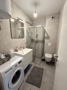 a bathroom with a shower and a washing machine at Apartman Barbara in Ljubuški