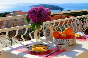 a table with plates of fruit and a vase of flowers at Apartments Tonći and Iris in Primošten +30 photos