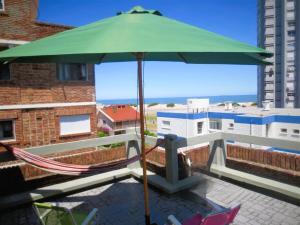 a green umbrella sitting on top of a balcony at APARTAMENTO 1 DORMITORIO EN PUNTA DEL ESTE in Punta del Este