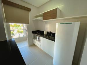 een kleine keuken met witte kasten en een raam bij Apartamento por Temporada Veredas Flat - Rio Quente Goias in Rio Quente