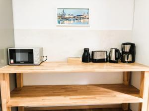 ein Holzregal mit einer Mikrowelle und Kaffeemaschinen darauf in der Unterkunft Apartment-Haus Landeskrone in Dresden