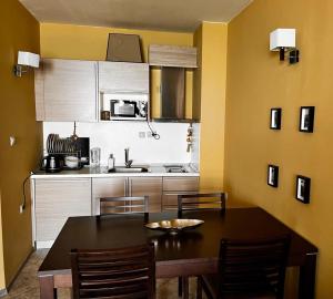 a kitchen with a table and chairs and a kitchen with yellow walls at Sirena apartament First Line in Golden Sands