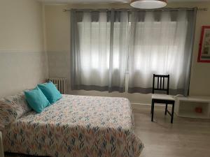een slaapkamer met een bed met blauwe kussens en een stoel bij Céntrico Hospedaje en Vigo in Vigo