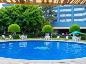 a large swimming pool with chairs and an umbrella at Grand Cantalagua Hotel Morelia, BW Signature Collection in Morelia