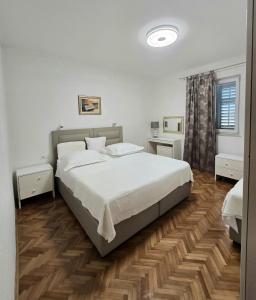 a bedroom with a large white bed and wooden floors at Adam apartments in Stobreč +46 photos