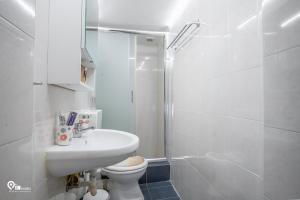 a white bathroom with a sink and a toilet at Omiros - Spacious Seaside House At Poros in Poros
