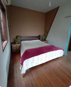 a bedroom with a bed with a red blanket on it at Suite no Paraiso! Uma experiência única de paz! in São Vicente
