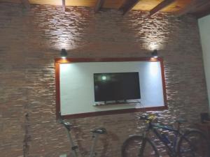 ein Flachbildfernseher an einer Ziegelwand mit zwei Fahrrädern in der Unterkunft Sol y Playa in Mar del Plata