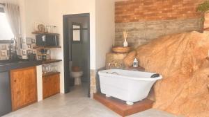 a bathroom with a bath tub and a large rock at Pousada Studio Siriú, Rocha in Garopaba