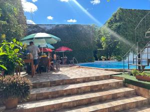 a group of people sitting under umbrellas near a swimming pool at La Posada del Cauchero Hotel & Suites in Iquitos