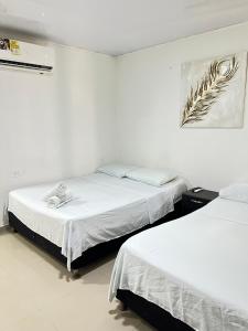Dos camas en una habitación con paredes blancas. en Tropical Dreams, en San Andrés