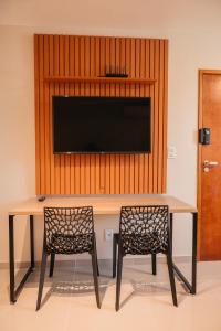 a table with two chairs and a television on a wall at LOFT Sofisticado na Praia de Vila - Centro in Saquarema