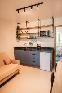 a kitchen with a sink and a couch in a room at LOFT Sofisticado na Praia de Vila - Centro in Saquarema