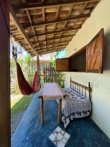 a patio with a table and a hammock in a room at Casa de Deli in Ilha de Boipeba