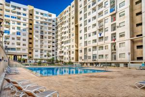 an apartment complex with a swimming pool in front of buildings at Bel appartement piscine, 10 min stadium, souk, plage, bein sports in Agadir